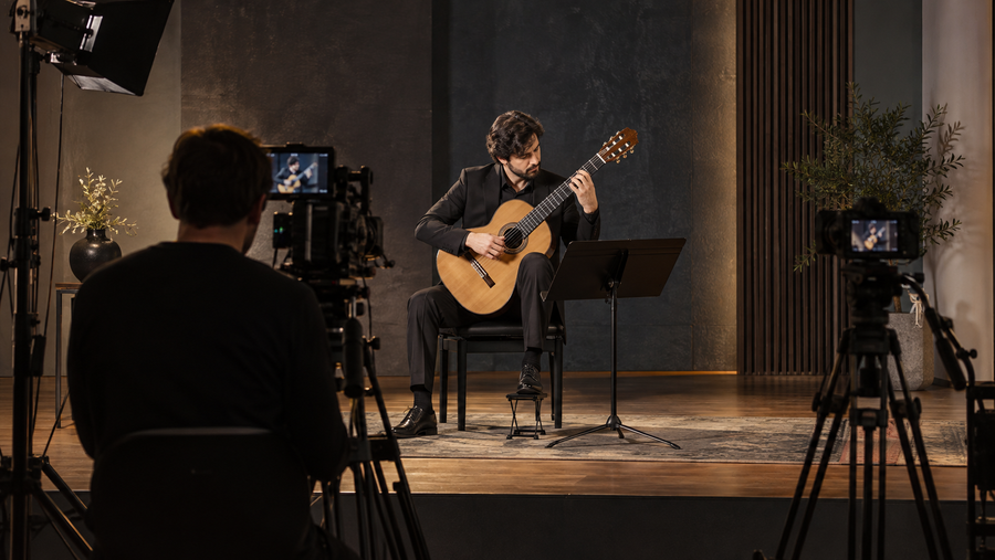 Classical guitar performance being filmed with professional camera and lighting equipment